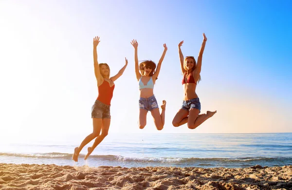 Felices amigos sonrientes saltando en la playa — Foto de Stock