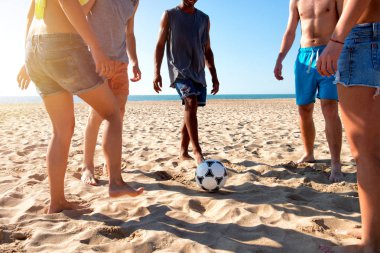 Sahilde futbol oynayan bir grup arkadaş