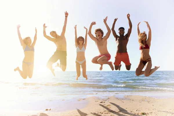 Felices amigos sonrientes saltando en la playa — Foto de Stock