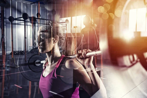 Athletic girl works out at the gym with a barbell. Female, healthy. Double exposure