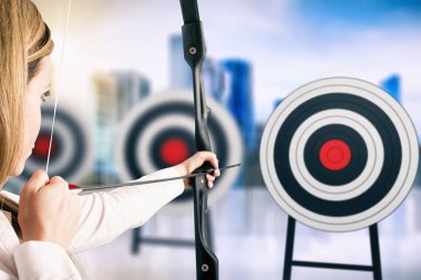 Businesswoman with bow and arrow pointing the center of the target clipart
