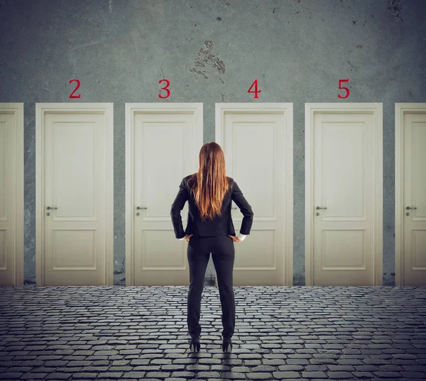 Businesswoman looking to select the right door. Concept of confusion and competition — Stock Photo, Image