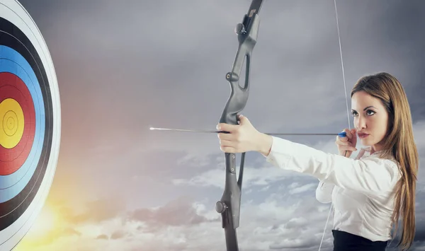 Businesswoman with bow and arrow pointing the center of the target. — Stock Photo, Image