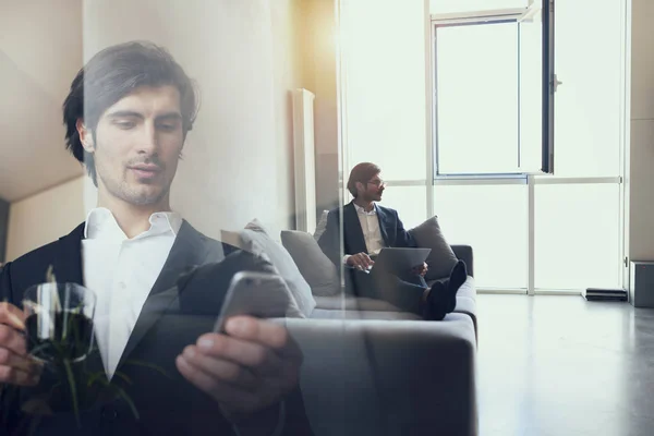 Geschäftsmann arbeitet im Büro mit seinem Smartphone. Doppelbelastung. — Stockfoto