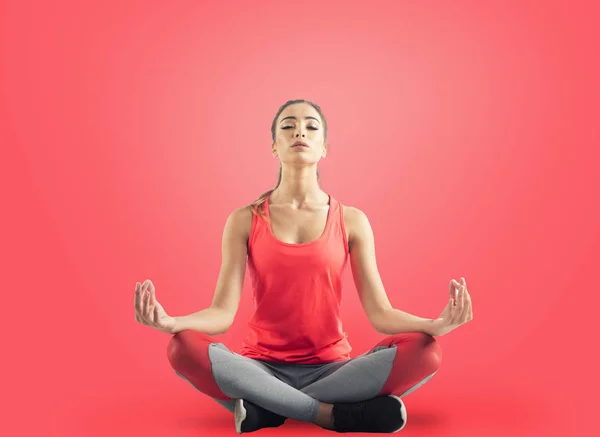 Chica joven relajándose en posición de yoga sobre fondo rojo —  Fotos de Stock