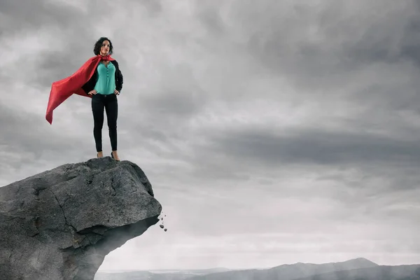 Mujer de negocios como superhéroe en la cima de una montaña — Foto de Stock