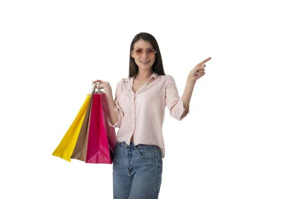 Happy woman with shopping bags in hand indicates something — Stock Photo, Image