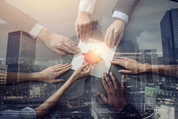 İş adamları yapboz parçalarını ofiste birleştiriyor. Takım çalışması ve ortaklık kavramı. Işık efektleri ile çift pozlama