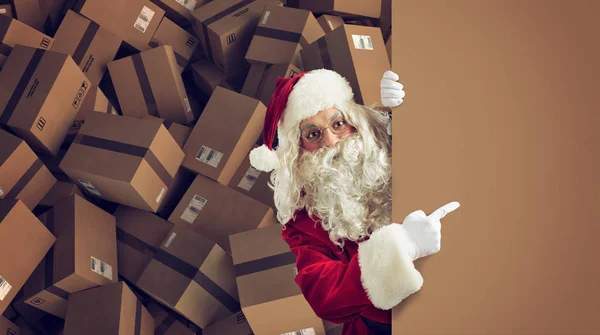Santa Claus indica un espacio para la Navidad presente, con paquetes listos en el fondo — Foto de Stock