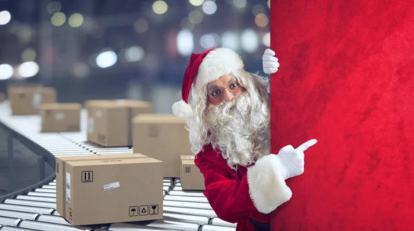Kerstman duidt een ruimte aan voor de aanwezige Christimas, met kant-en-klare pakketten op de achtergrond — Stockfoto