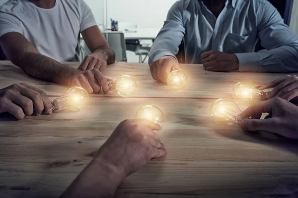 Trabajo en equipo y el concepto de lluvia de ideas con hombres de negocios que comparten una idea con una lámpara. Concepto de startup — Foto de Stock