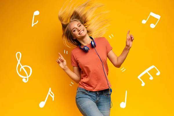 Blondes Mädchen hört Musik mit Headset. fröhlicher Ausdruck auf gelbem Hintergrund — Stockfoto