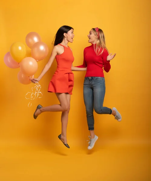 Chicas listas para una fiesta con globos. Alegre expresión de felicidad. Fondo amarillo —  Fotos de Stock