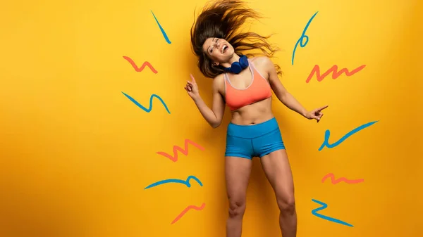 Fitness girl ascolta musica con auricolare. Espressione gioiosa e felice su sfondo giallo — Foto Stock