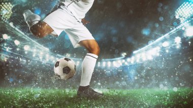 Gece bir futbol maçının kapanış sahnesinde beyaz üniformalı bir oyuncu topa güçlükle vuruyor.