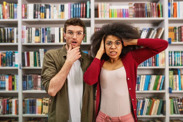 Jovem estudante com expressão preocupada em uma biblioteca — Fotografia de Stock