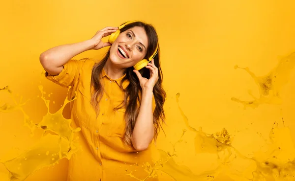 Ragazza con auricolare giallo ascolta musica e balli. espressione emotiva ed energetica — Foto Stock