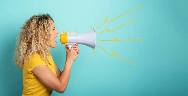 La mujer grita con un altavoz. expresión enojada. antecedentes de cyan — Foto de Stock