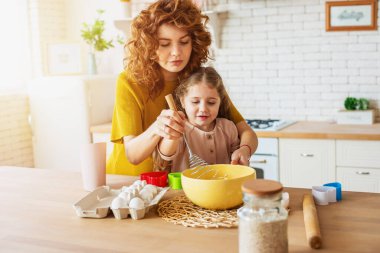 Anne ve kızı mutfakta birlikte bir pasta hazırlıyorlar.