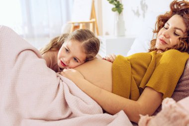 Hamile anne kızıyla oynuyor. Aile kavramı, neşe ve hamilelik