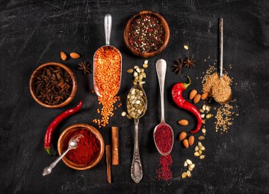 Kaşık içinde renkli baharatlar. Koyu taş masada..