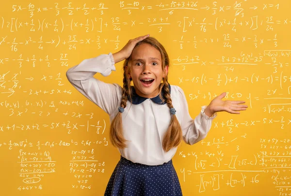 Genç öğrenci matematik probleminin zorluğuna hayret ediyor. Sarı stüdyo arka planı — Stok fotoğraf