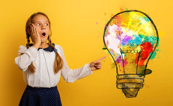 Junge Studentin hat eine neue Idee mit einer großen Glühbirne. Gelber Hintergrund — Stockfoto