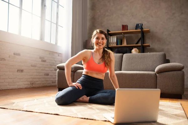 Young girl follows with a laptop a gym exercises. She is at home due to coronavirus codiv-19 quarantine — Stock Photo, Image