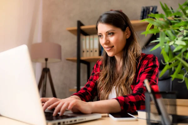 Kız tele-işçi evde dizüstü bilgisayarla çalışıyor.