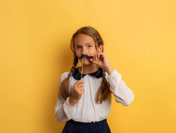 Young student acts like a senior teacher. Yellow studio background — Stock Photo, Image