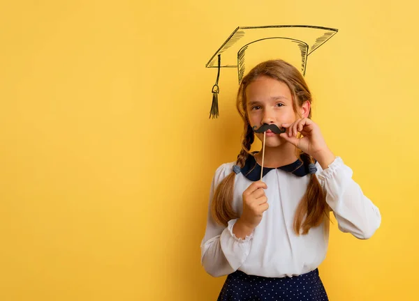 Young student acts like a graduate. Yellow studio background — Stock Photo, Image