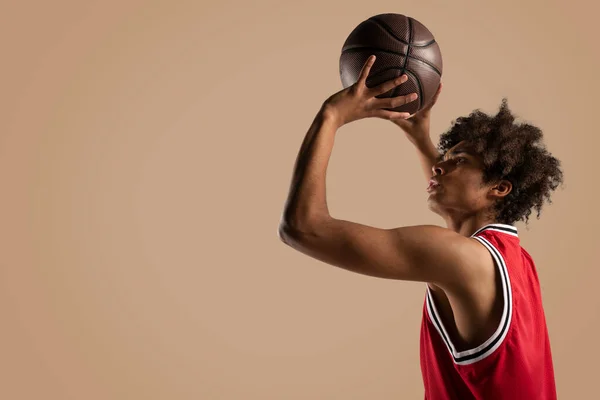 Jugador de baloncesto lanza la pelota sobre fondo marrón . — Foto de Stock