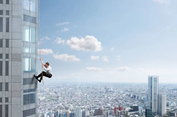 Businessman climbs a building with a rope. Concept of determination. — Stock Photo, Image