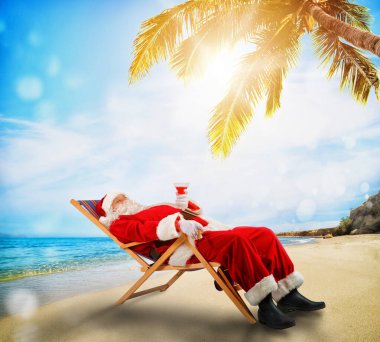 Noel Baba tropik bir plajda güverte sandalyesinde dinleniyor.