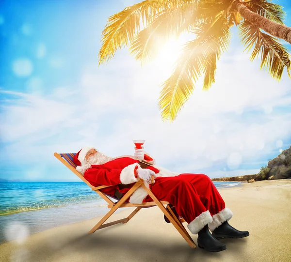 Święty Mikołaj relaksujący się na leżaku w tropikalnej plaży — Zdjęcie stockowe