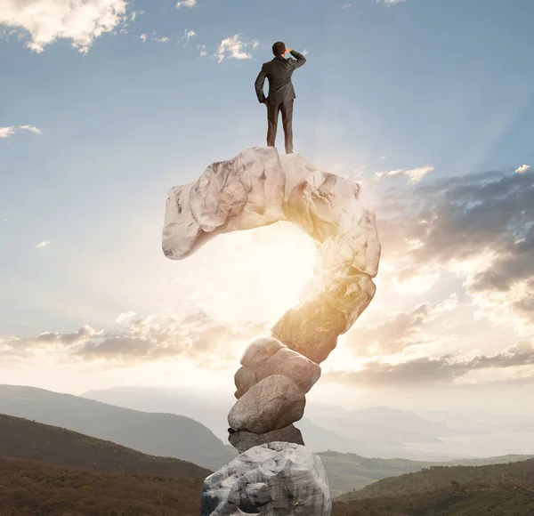 Zakenman over een berg in de vorm van vraagteken kijkt naar de toekomst — Stockfoto