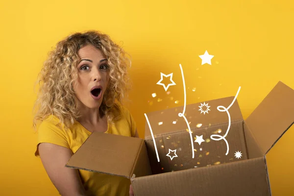 Ragazza felice riceve un pacchetto da ordine negozio online. sfondo giallo. — Foto Stock