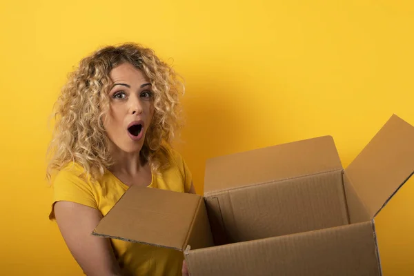 幸せな女性はパッケージからオンラインショップ注文。黄色の背景. — ストック写真