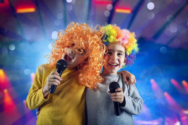 Zwei Kinder singen ein Lied mit Mikrofon und lustiger Perücke — Stockfoto