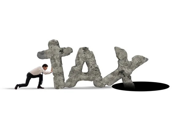 Businessman pushes the word TAX made of heavy rock in a black hole — Stock Photo, Image
