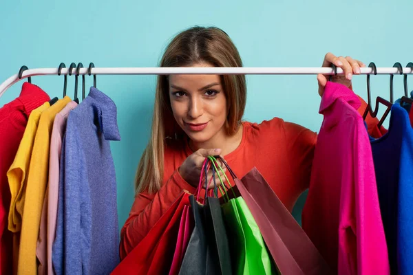 Donna bionda sceglie i vestiti da acquistare in un negozio. Concetto di shopping e shopaholic. — Foto Stock