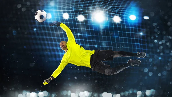 Portero de fútbol, en uniforme fluorescente, que hace un gran ahorro y evita una meta sobre un fondo azul oscuro — Foto de Stock