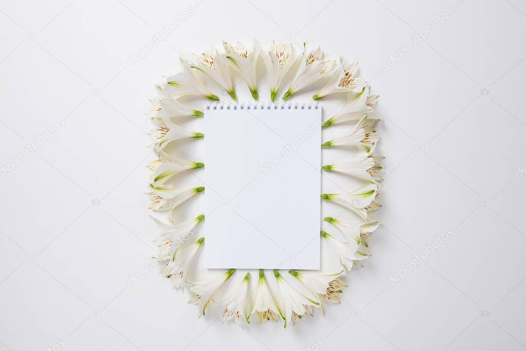 The notebook surrounded by white Alstroemeria flowers and text space