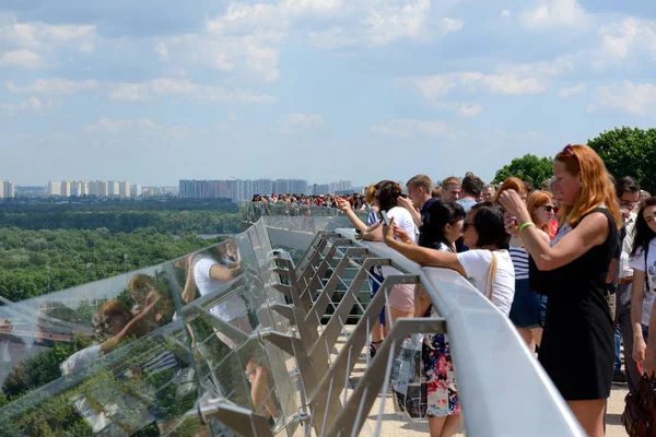 KYIV, UCRANIA - 26 DE MAYO: El grupo de personas está en el nuevo puente peatonal que conecta el Arco de la Amistad Popular y Volodimir el Gran monumento el 26 de mayo de 2019 en Kiev, Ucrania. Puente han sido abiertos el 25 de mayo por el alcalde de Kiev Vitaliy Klichko — Foto de Stock