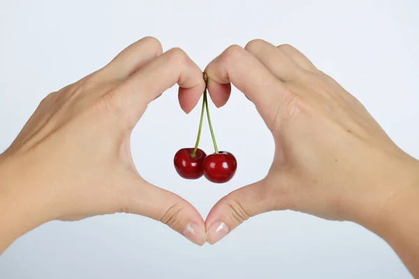 The hands with heart shape (love consept) and cherry inside on white background