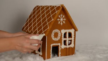 Çatı ve kar dekorasyonu üzerinde buzlanma elle ekleyerek, el yapımı yiyilebilir Gingerbread ev