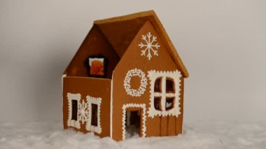 El yapımı yiyilebilir Gingerbread ev, çatı ve kar dekorasyonu parçası elle ekleyerek