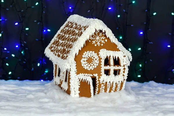 A casa de gengibre comestível feita à mão, decoração de neve, iluminação de fundo de guirlanda — Fotografia de Stock