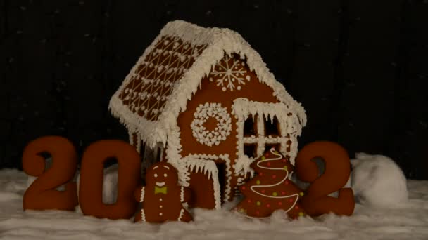 手作りの食べられるジンジャーブレッドハウス 2020年の碑文にゼロの手で追加 小さな男 新年の木 雪の装飾 花輪の背景照明 — ストック動画