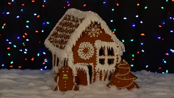 手作りの食べられるジンジャーブレッドハウス 小さな男 新年の木 雪の装飾 花輪の背景照明 — ストック動画